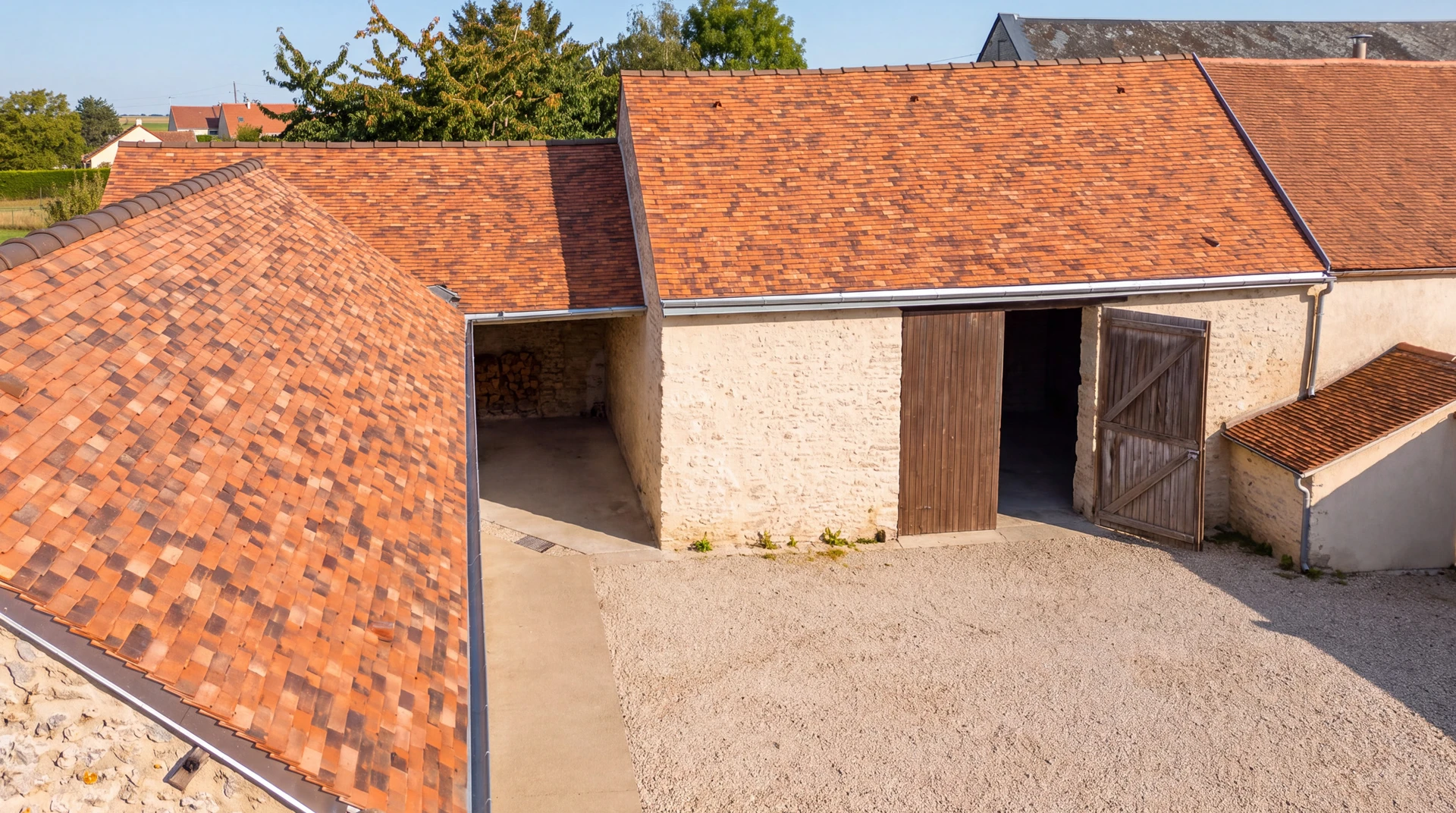 Couvreur en tenue de travail posant des ardoises naturelles grises rectangulaires sur un versant de toiture en rénovation, crochets inox apparents, liteaux bois visibles, geste de fixation en cours, charpente et sous-toiture en arrière-plan.